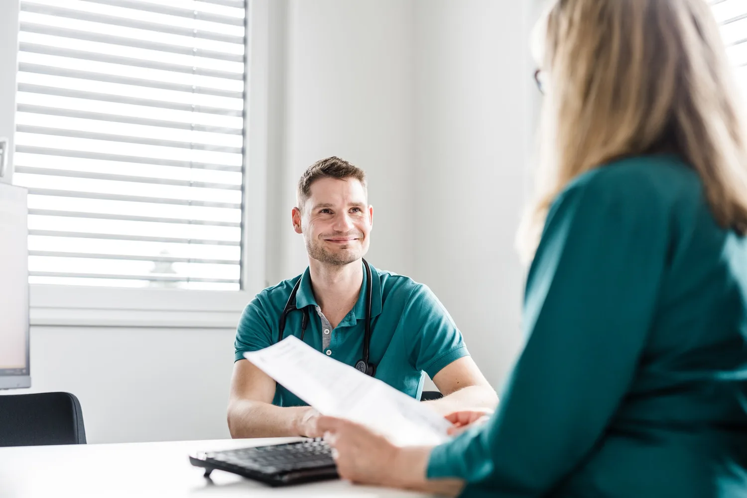 Arzt im Gespräch mit einer Patientin am Schreibtisch