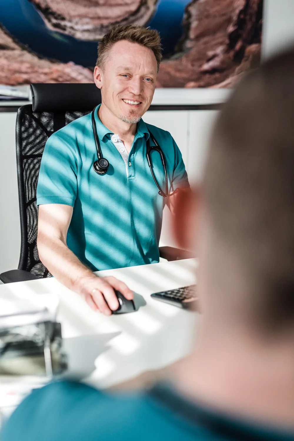 Arzt am Bildschirm im Gespräch mit einer Patientin